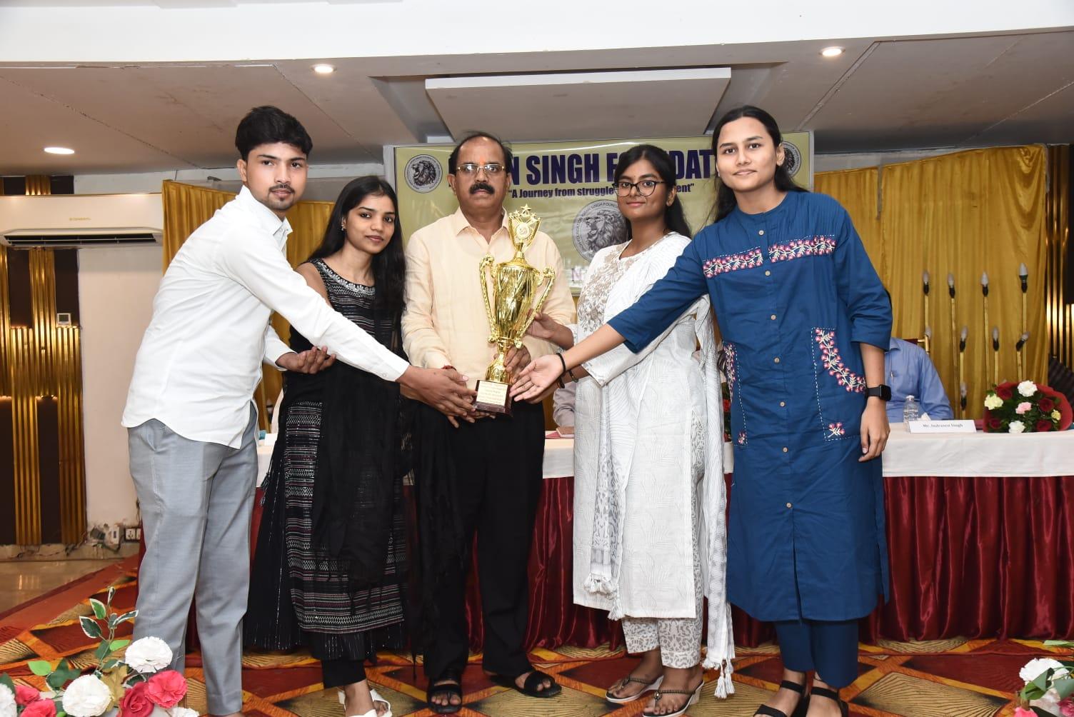 Unnaati Roy (HSM) receiving the inaugural excellence trophy in front of the official foundation banner